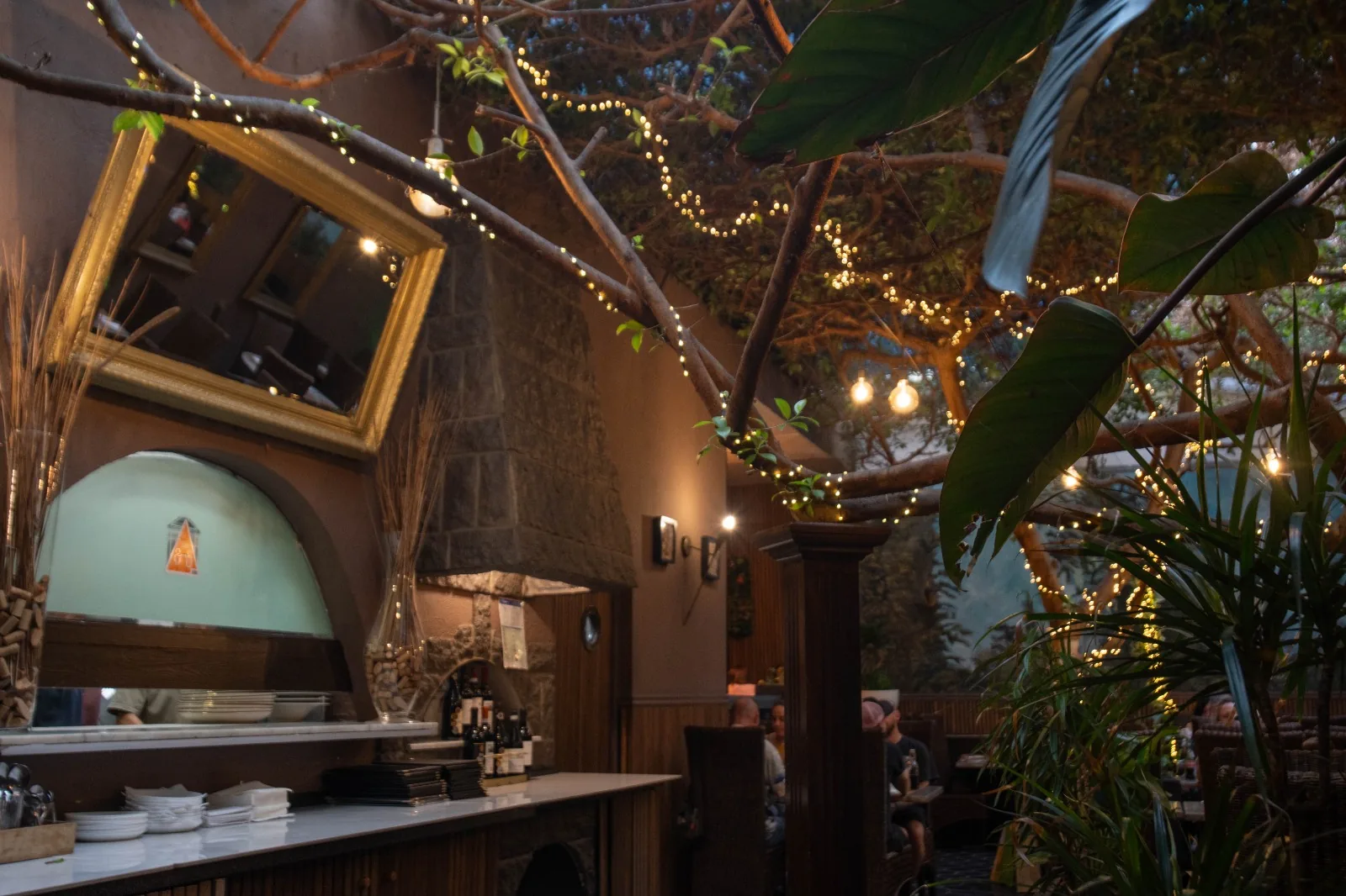 Bar, miroir doré et plantes sous les ficus