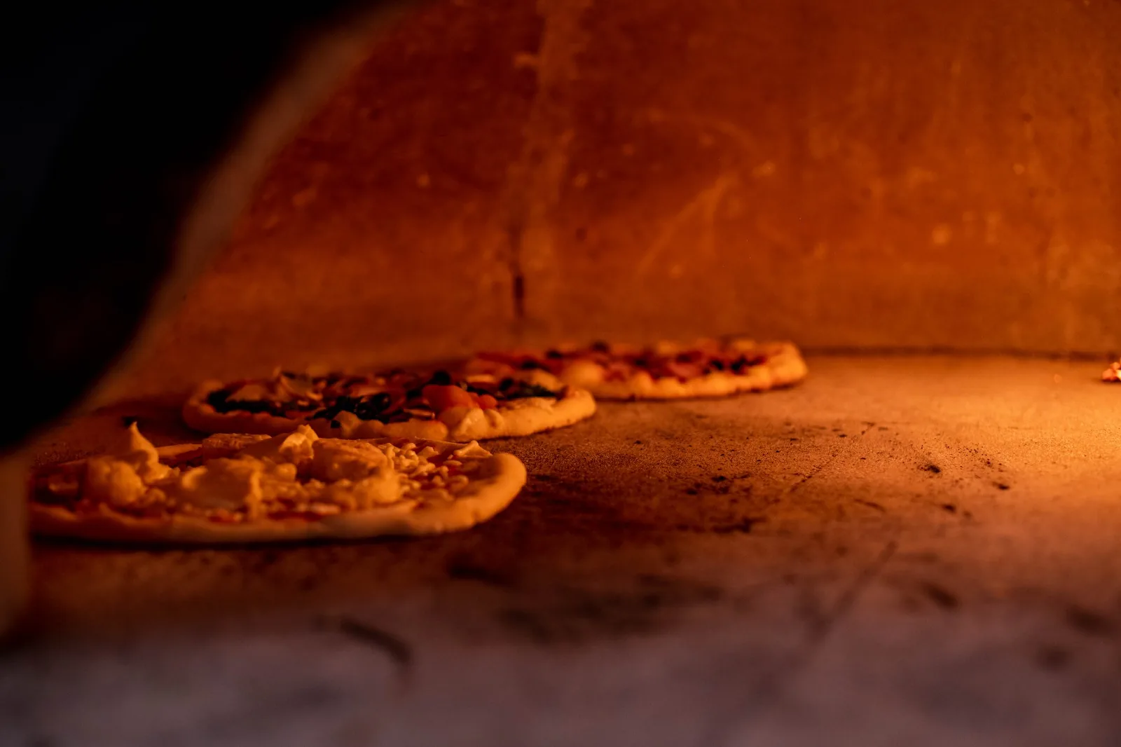 Pizzas en cuisson dans le four à bois